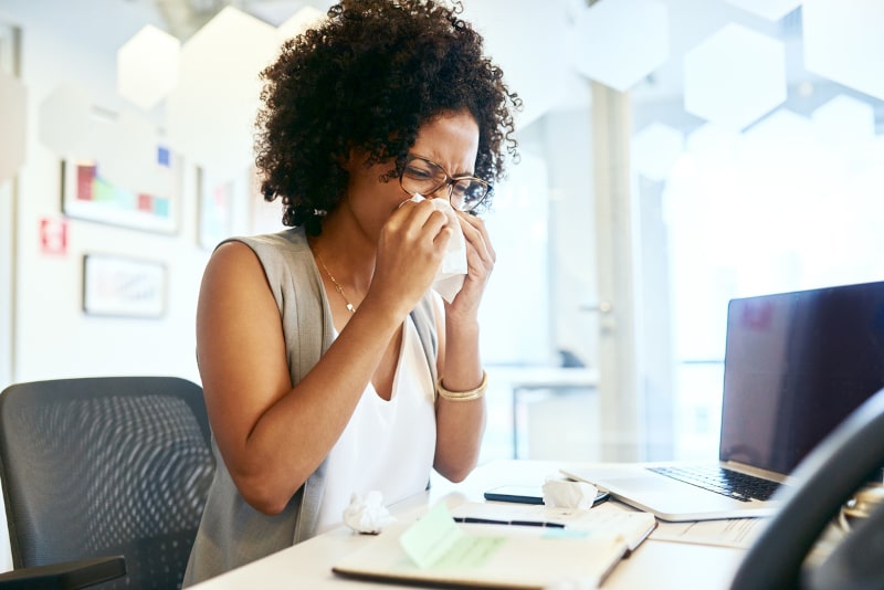 Young Woman Sneezing In Office Young Woman Sneezing In Office